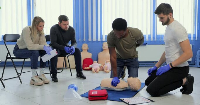Group of people CPR First Aid Training course. CPR teen dummy first aid training.