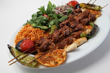 Turkish kebab lamb meat on skewer.
with vegetables and rice on a serving plate
