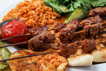 Turkish kebab lamb meat on skewer.
with vegetables and rice on a serving plate