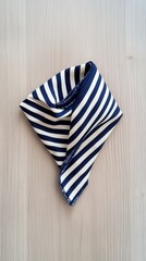 Obraz premium A navy and white striped handkerchief on a light wood table, perfect for nautical decor