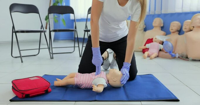 Practitioners training medical learning on a baby mannequin. Giving first aid on a child dummy. First aid training.