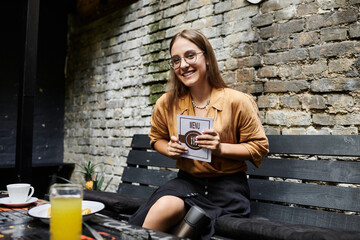 In a lively cafe, a young woman with an artificial limb eagerly holds the menu, sharing her vibrant...