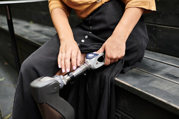 At a cozy cafe, a young woman showcases her artificial limb, embracing her daily lifestyle with grace and confidence.