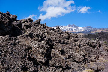 Volcanic rocks with volcano in background with blue sky