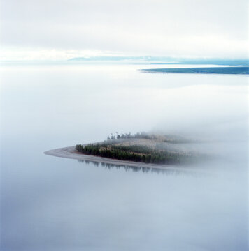 Aerial view of serene lake with fog and an island in a tranquil landscape, eastern siberia, russia.