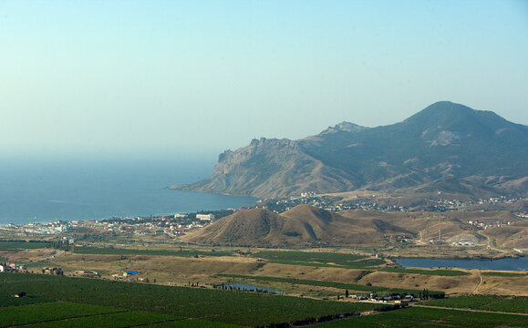 Aerial view of picturesque coastline and tranquil sea with distant mountains and a serene village, Koktebel, Crimea Autonomous Region, Russia.