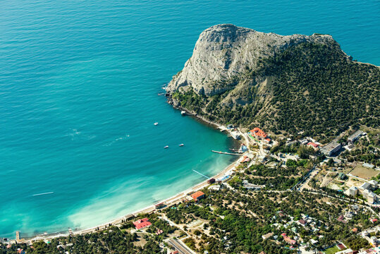 Aerial view of tranquil turquoise sea and sandy beach along a picturesque coastline with mountains, Novyi Svit, Russia.