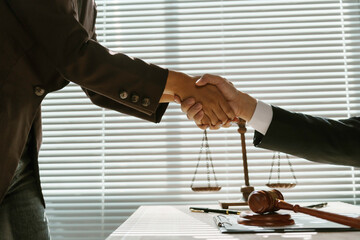 Two lawyers shaking hands after reaching an agreement during a legal trial, with scales of justice...