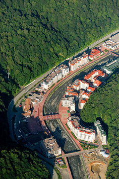 Aerial view of beautiful urban landscape with modern buildings, river, and lush greenery, Krasnaya Polyana, Russia.
