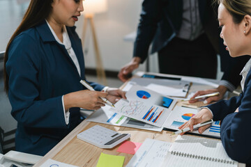 Businesswomen working together, analyzing financial charts, graphs and data for marketing strategy at office