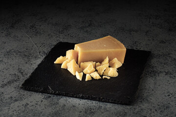 Authentic Italian Parmigiano Reggiano: Aged Cheese Slice on Black and Wooden Backgrounds