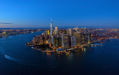 Aerial view of illuminated financial district skyline at night with beautiful reflections on the East River, New York, United States.