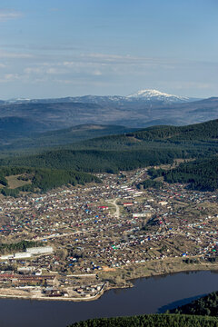 Aerial view of beautiful Beloretsk town surrounded by scenic forest and river with mountains in the background, Bashkortostan Republic, Russia.
