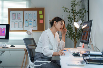 Young female web designer working on user interface and experiencing stress and fatigue in her...