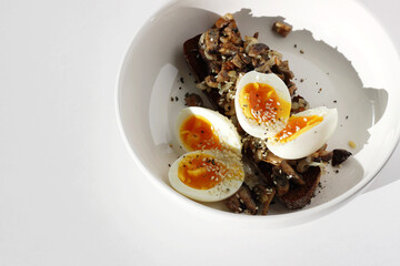 Breakfast. Soft Boiled Eggs on Rye Toast with Forest Mushrooms Served in Bowl Plate on White Table. 