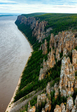 Aerial view of majestic rock formations and a tranquil river surrounded by forests and cliffs, Lena Pillars National Park, Russia.