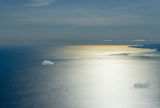 Aerial view of serene and tranquil Baikal Lake with sunlight reflection and expansive sky, Irkutsk Region, Russia.