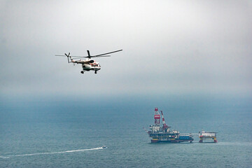 Russia - 10 November 2017: Aerial view of offshore oil rig in the caspian sea with a helicopter above, Russia.