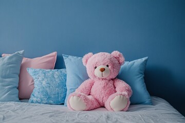 A fluffy pink teddy bear sitting on a cozy bed next to soft blue and pink pillows during a tranquil evening