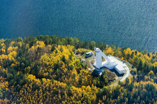 Aerial view of Baikal Lake and Angara River surrounded by autumn foliage and a large solar vacuum telescope, Listvyanka, Russia.