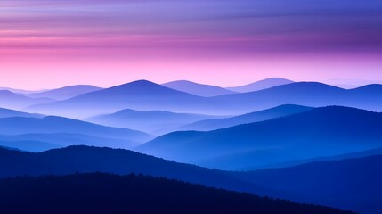 Obraz premium A misty mountain range at dusk with deep blue and purple hues in the sky
