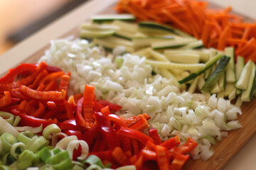 Chopped leek, red pepper, onion, zucchini and carrot on the chopping board. Cooking and meal prepping at home. Selective focus.
