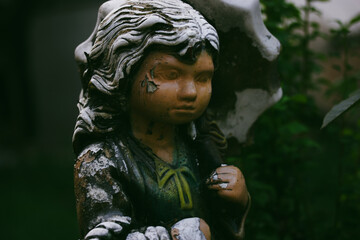 Worn stone angel. Vintage female figurine with shabby paint on her face. Monument in a cemetery....