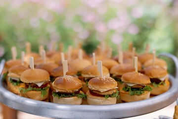 Mini burgers on a tray with garden backdrop