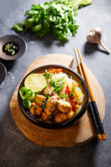 A bowl of glass or cellophane noodles with Asian caramelized chicken breast on table vertical photo
