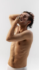 Obraz premium Close-up of young man with wet hair, soft, natural hairstyle, posing in underwear against grey studio background. Concept of natural beauty, male health, fashion, skin care. Ad