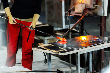 Close-up glassblowing process tube tool with molten glass shaped inside refractory furnace in...