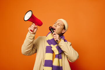 A young man with tattoos passionately speaks into a megaphone while wearing a stylish scarf.