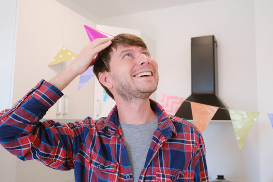 Young man celebrates his birthday at home, surrounded by a cozy and festive setting. He enjoys his special day , creating memories , preparing for the holiday, decorating the room - Powered by Adobe