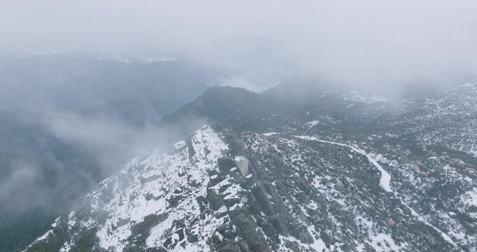 Aerial view of snow-covered Mount Buffalo with clouds in a scenic winter landscape, Victoria, Australia.