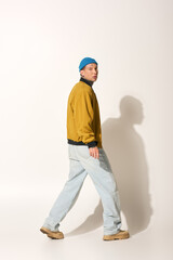 Fototapeta premium A tattooed young man walks confidently in a stylish jacket and casual pants.