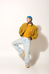 A young man with striking tattoos showcases his fashion sense while posing artistically.
