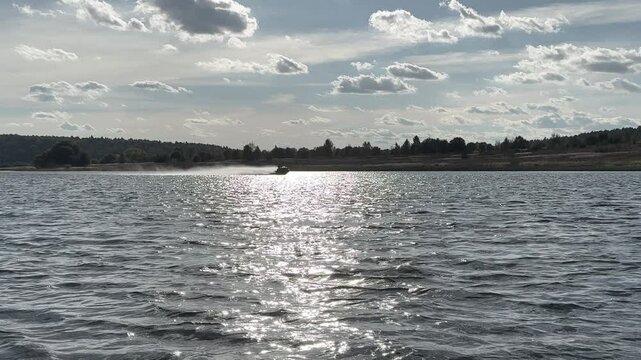 High speed jet ski on river, horizon of waves with sun reflection and clear sky. Water sports, jet ski, extreme water recreation