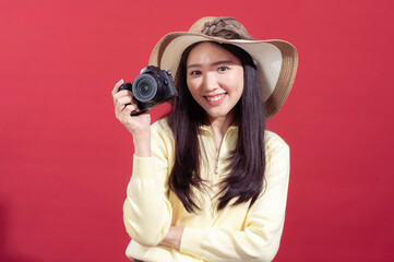 Asian woman in a yellow sweater holding a camera up to her face, as if taking a photo, with one eye...