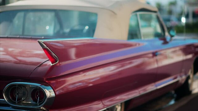 Close up of the side of a burgundy, retro car parked on the street