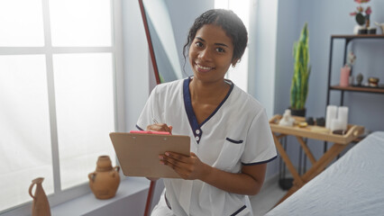 Woman writing notes in spa salon with clipboard, smiling friendly in wellness center, indoor setting