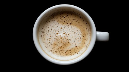 Top view of a coffee cup filled with frothy milk set against a black backdrop