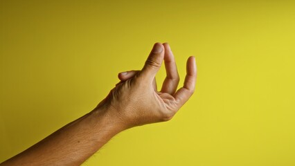 Naklejka premium Man's fingers forming a gesture with a yellow background, emphasizing hand details and skin texture under bright natural light.