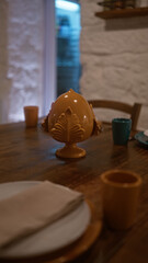A cozy italian restaurant interior in italy with a close-up of a wooden table set for dining, featuring ceramic tableware, napkins, and decorative elements, creating a warm, inviting atmosphere.