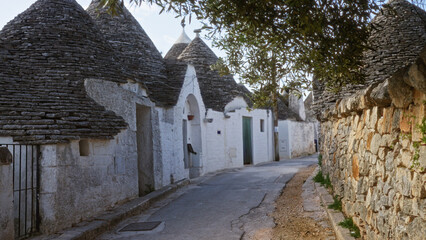 A quaint town in alberobello, italy, featuring traditional trulli houses with conical roofs on a...