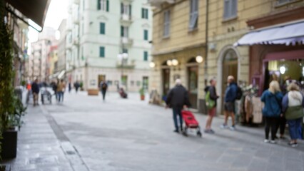Street scene in la spezia, italy with blurred pedestrians, showcasing a vibrant town with defocused buildings and soft bokeh capturing a casual european atmosphere.