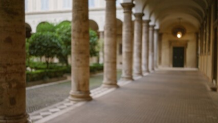 Blurred image of an old university campus exterior with stone columns, featuring a defocused view of a courtyard showcasing architectural elegance and classic design.