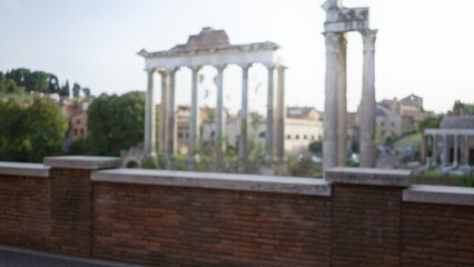 Obraz premium Blurred view of the historic roman forum ruins with ancient columns under a clear sky, capturing the timeless essence of rome's architectural grandeur.