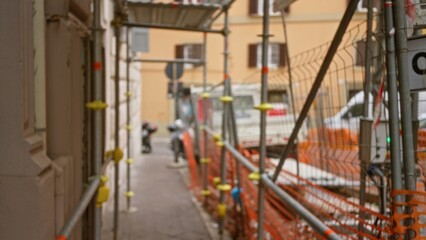 Defocused urban construction site with scaffolding featuring blurred workers in the background and bokeh effects in daylight.