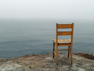  Wooden chair facing an expansive foggy ocean, evoking solitude, reflection, and contemplation in a minimal, serene setting.