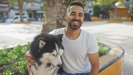 Smiling hispanic man with husky dog sitting in city park © Krakenimages.com